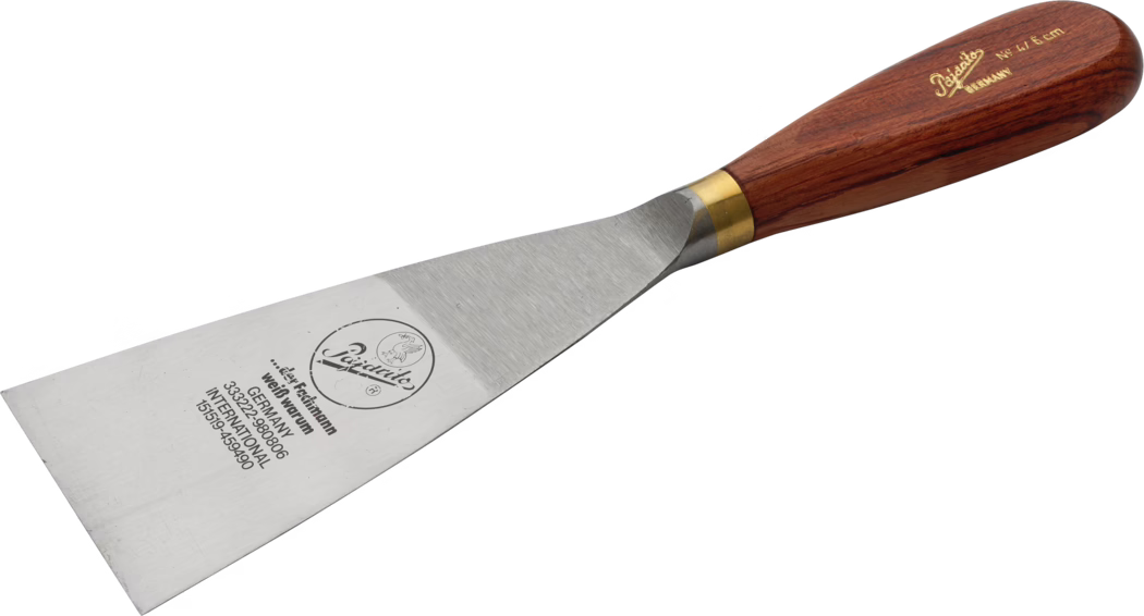Pajarito_Dummy_Goiter spatula precious wood w brass_034461_034459_060041_060042_060043_034497_2021-02 Spachtel aus Stahl mit breiter rechteckiger Klinge und Holzgriff mit Messinghülse; auf der Klinge sind Markenlogo und Prägung zu sehen. Werkzeug zum Schaben und Auftragen von Spachtelmasse. Aufnahme auf weißem Hintergrund in leicht schräger Ansicht.